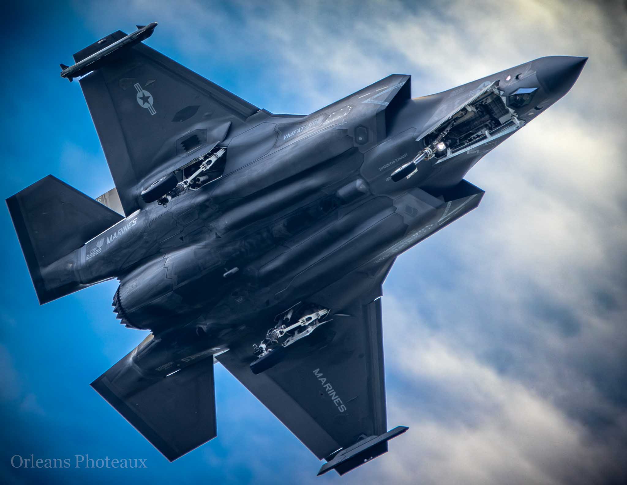 Two military jets banking together against a blue and clouded sky
