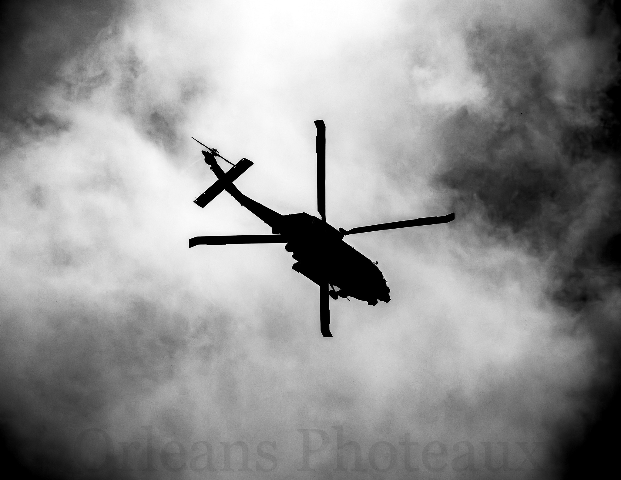 Black-and-white silhouette of a helicopter against dramatic clouds