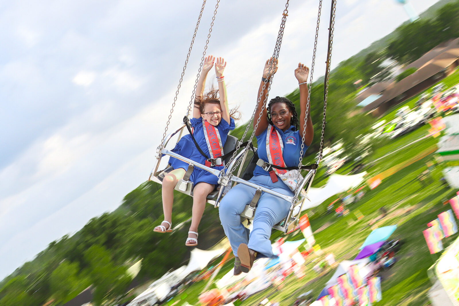 Festival queens laughing together on a moving carnival ride