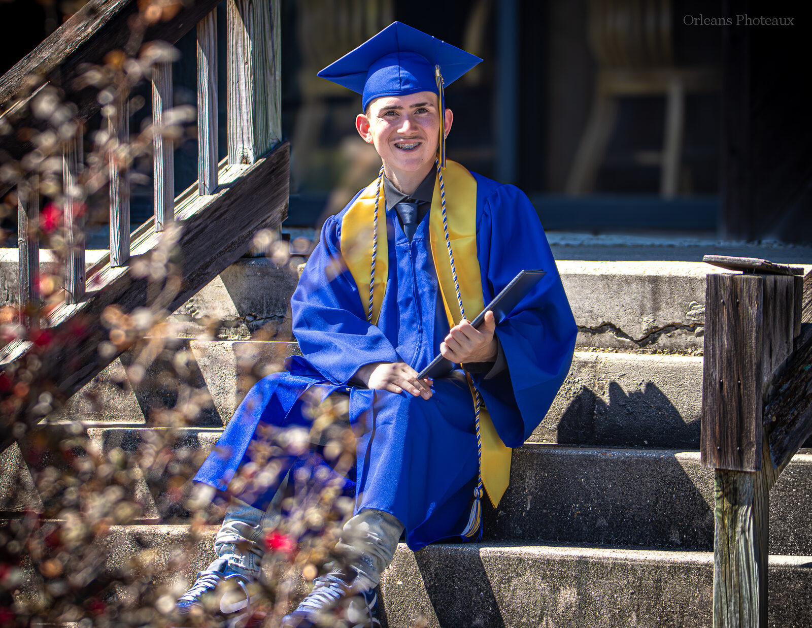 A graduating senior seated outdoors in cap and gown